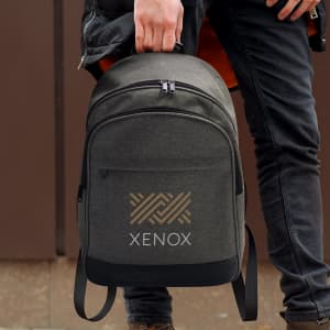A grey backpack with a logo, being held by a person wearing dark clothing.