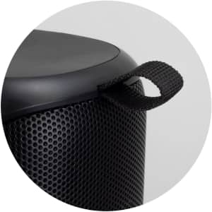 A black Bluetooth speaker featuring a textured surface and a carry strap. The design is compact and cylindrical.
