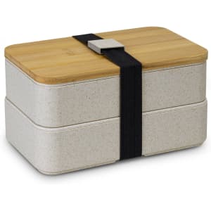 A stackable lunch box in a light grey colour with a bamboo lid and secured by a black strap.