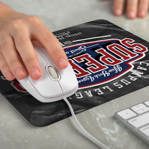 A slimline black mouse mat featuring a logo, with a white computer mouse resting on it and a desk surface underneath.