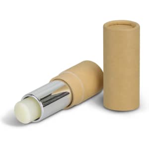 A lip balm in a silver and natural cardboard tube, with the tube's cap beside it. The balm appears to be a light colour.