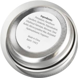 A silver lip balm tin with a round shape, showing a label with ingredient details on the top.