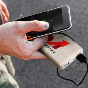 A power bank in a light colour with a logo, being used to charge a smartphone.