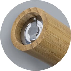 A bamboo pepper mill featuring a stainless steel grinding mechanism and smooth wooden finish. It has a logo inside.