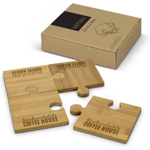 A set of four bamboo puzzle coasters in a brown box, featuring engraved text and a logo.