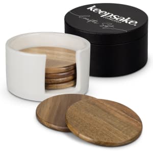 A set of wooden coasters in a white holder, with a black round container featuring branding.