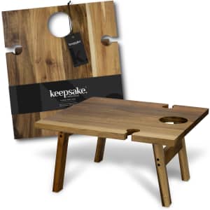 A wooden folding wine table with a circular cutout, featuring a warm, natural finish and a logo tag.
