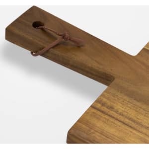 A wooden chopping board with a natural finish and a leather tie attached for hanging.