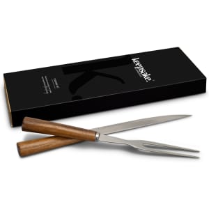 A carving fork with wooden handles and a sleek stainless steel prong, presented in a black box with logo.