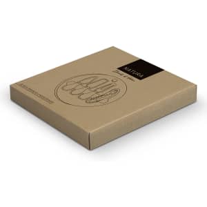 A square kraft packaging for the NATURA Glass & Bamboo Cheese Board, featuring simple line art and a logo.