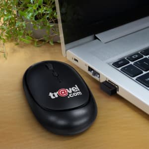 A wireless travel mouse in black, positioned next to a laptop with a USB receiver plugged in.