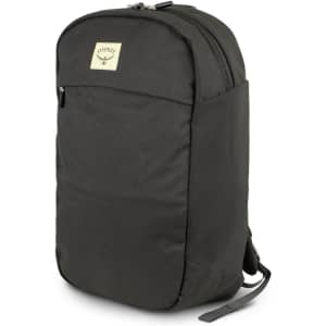A dark green backpack with a logo on the front, featuring a slim design and zippered compartments.