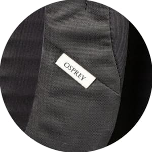 A close-up of a black fabric section featuring a small Osprey logo tag.