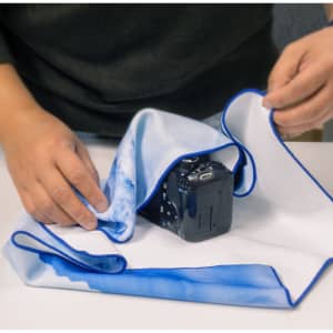 A large, blue and white patterned cloth is being used to cover a camera on a table.