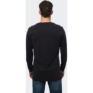 A man wearing a black long sleeve crew shirt, shown from the back, with denim jeans. The shirt features a logo.