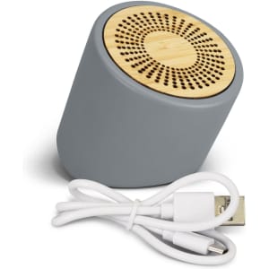 A grey Bluetooth mini speaker with a bamboo grill, accompanied by a charging cable.