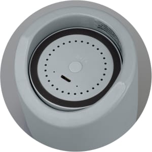 A Bluetooth mini speaker in light grey with a circular base and a small charging port at the bottom.