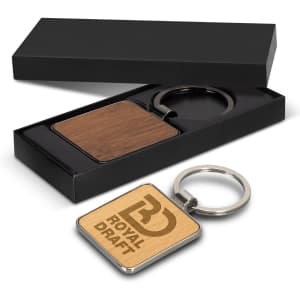 A square wooden key ring with a metallic keychain, presented in a sleek black box.
