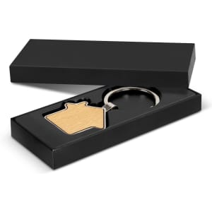A house-shaped key ring in a black presentation box, featuring a wooden front and metal ring.