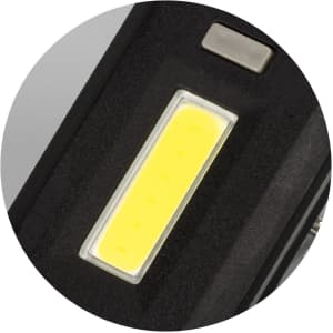 A close-up of a black key ring light featuring a bright yellow COB LED strip and a metal button.