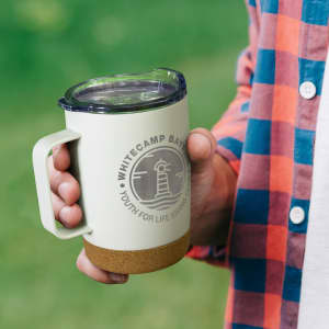 A drink bottle in light green with a cork base and a clear lid, featuring a logo on the front.