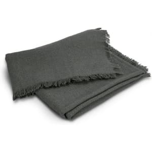 A green herringbone throw blanket with fringed edges, folded neatly on a white background.