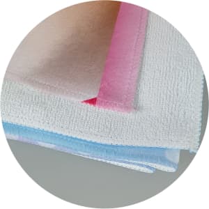 A stack of soft beach towels in pastel colours, featuring a logo on one of the towels.