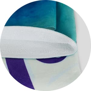 A full-colour beach towel featuring vibrant blue, green, and purple designs, with a white terry backing and a logo.