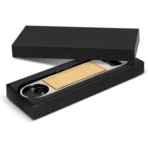 A drink bottle opener in a black box, featuring a metallic opening mechanism and a textured, gold-coloured grip.