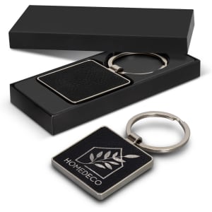 A square black key ring with a silver keychain, packaged in a sleek black box. Features a logo on the key ring.