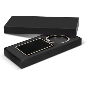 A rectangular black key ring with a metallic finish, presented in a sleek black box.