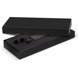 A black gift box containing a black key ring and a rectangular tag. The box is sleek and presents an elegant design.