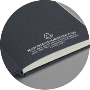 A dark grey hard cover notebook made from recycled cotton, featuring an embossed logo on the front.