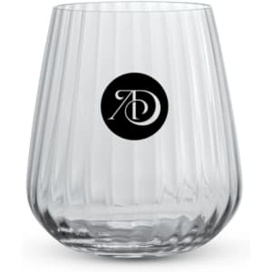 A clear stemless lowball glass with a ribbed design and a circular logo on the front.