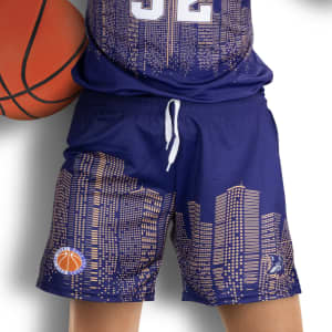 Custom women's basketball shorts in navy with a city skyline pattern and a logo. A basketball is being held.