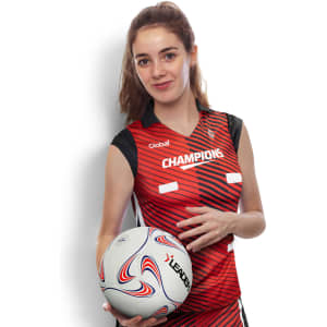 A woman in a red and black netball top holds a netball, featuring a logo on the uniform.