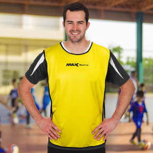A yellow custom training bib with black accents and a logo, worn by a smiling male model.