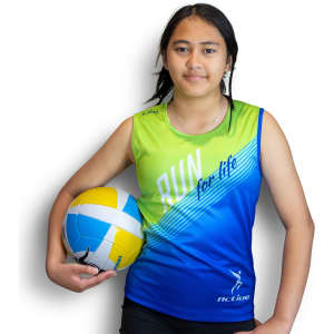 A girl in a green and blue sports singlet holds a volleyball, featuring a logo on the bottom.