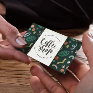 A hand holding a vibrant, full-colour loyalty card featuring a green design with various playful patterns and a logo.