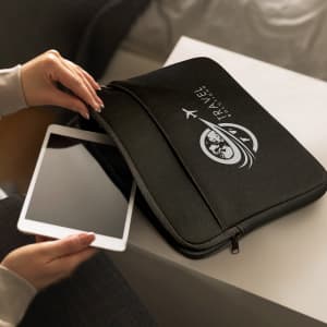 A small black laptop sleeve with a logo, being opened to reveal a tablet inside.