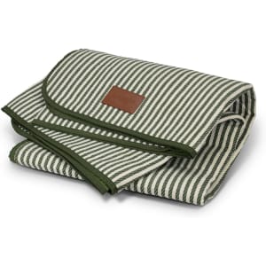 A folded picnic blanket featuring green and cream stripes, finished with a dark green trim and a small branded label.