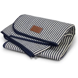 A folded picnic blanket with a navy and white striped design and a leather tag, showcasing a neat, compact appearance.