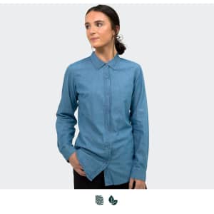 A denim button-up shirt in light blue, featuring a collar and long sleeves, with a logo present.