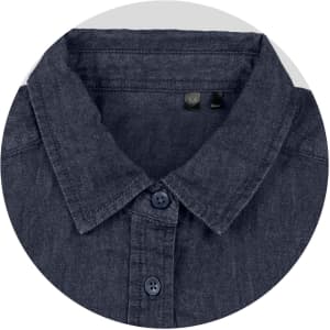A close-up of a dark denim button-up shirt with a collar and navy buttons. The shirt has a logo tag inside.