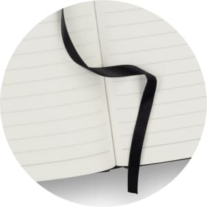 A black Petros Stone Paper Notebook with blank, lined pages and a black ribbon bookmark.