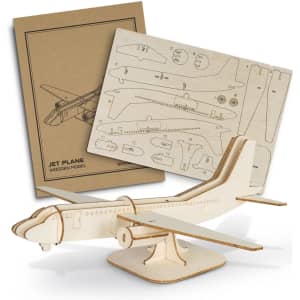 A wooden model of a jet plane in natural colour, with assembly instructions displayed behind it.