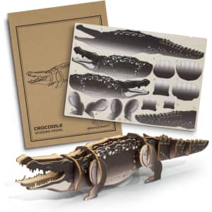 A wooden model of a crocodile in shades of brown and black, alongside a cardboard template with parts for assembly.