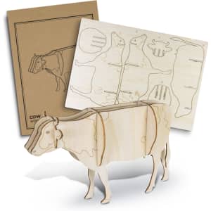 A wooden model of a cow in a natural finish, accompanied by a cardboard backing with cut-out designs.