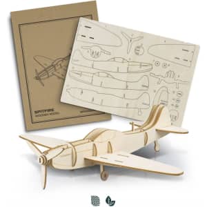 A wooden model of a Spitfire airplane in natural wood colour, displayed with its instruction sheet.