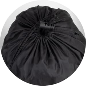 A black puffer blanket is rolled up and secured with a drawstring at the top. It has a smooth, shiny texture.